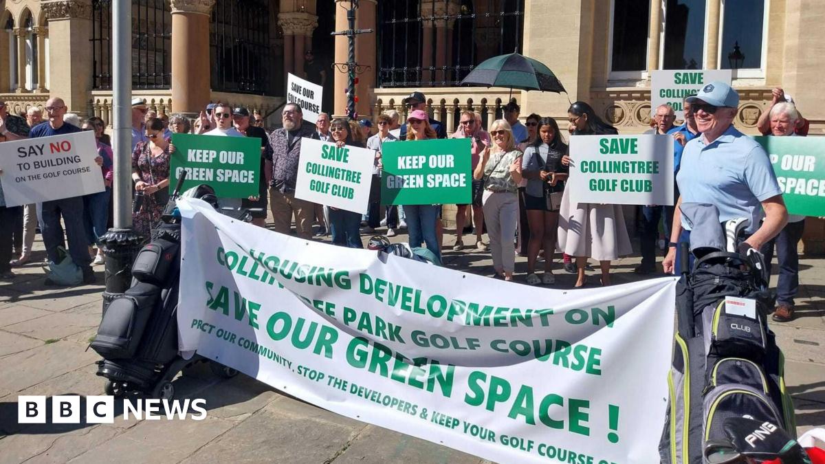 Lots of people stand in front of a stone building. They are holding green and white placards with "Keep our space" and "Save Collingtree Golf Club" written on them. There is also a large white banner bookended by two golf club bags with "Housing development on Collingtree Park Golf Course. Save our green space," written on it. It is a sunny day.