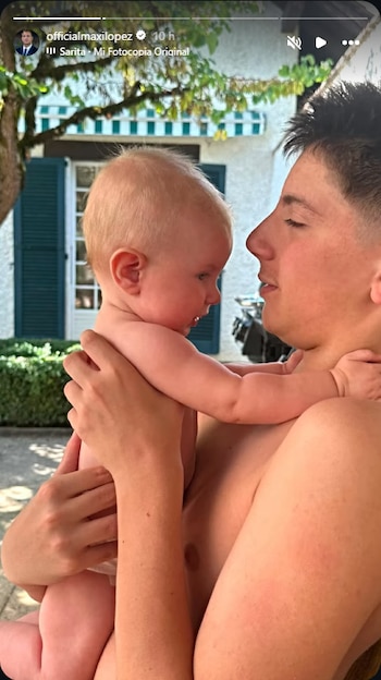 Hombre sin camiseta sosteniendo a un bebé, con un paisaje de fondo