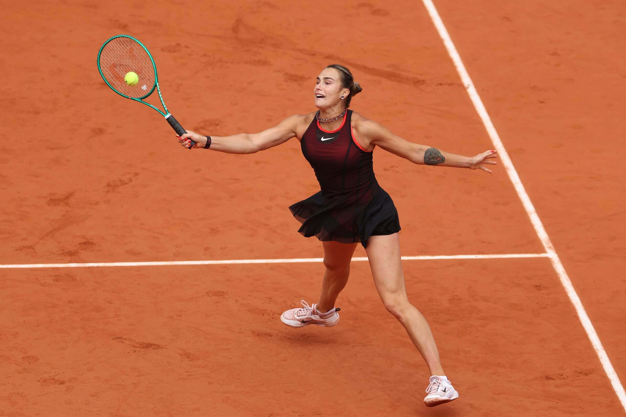 Aryna Sabalenka effectuant un coup en plein vol sur terre battue.